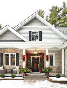 a house decorated for christmas with wreaths on the front door and decorations around the porch