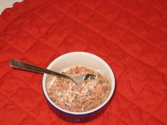 a bowl of cereal with a spoon in it on a red tableclothed placemat