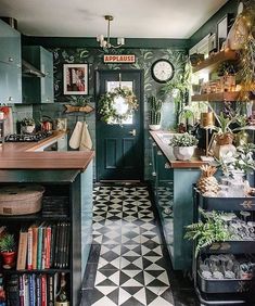 a kitchen with black and white checkered flooring, green cabinets and shelves filled with plants