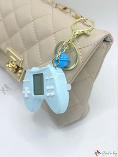 a keychain shaped like a video game controller is attached to a handbag