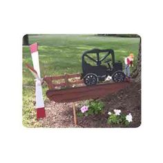 an old fashioned toy train is on display in the grass next to a flower bed