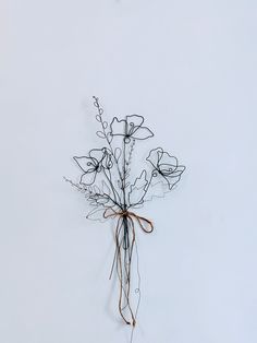 a bouquet of flowers tied to a wire on a white wall with no one around it