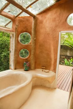 a bathroom with a large bathtub next to an open door and windows that look out onto the jungle