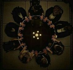 a group of people sitting around a table with their hands together