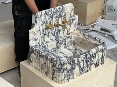 a marble sink is being worked on by a man in black and white shirt standing next to it