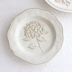 two white plates with flowers on them sitting next to each other