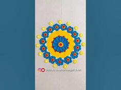 a blue and yellow wall hanging on the side of a white wall with an intricate flower design