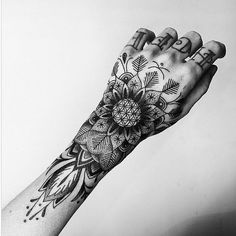 a black and white photo of a person's hand with an intricate tattoo design on it