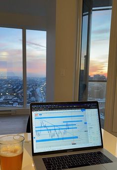 an open laptop computer sitting on top of a table next to a glass of beer