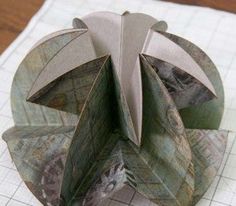 an origami sculpture sitting on top of a piece of paper