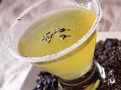 a glass filled with yellow liquid sitting on top of a table next to lavenders