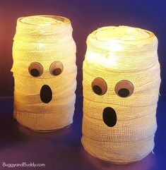 two wrapped up candles with googly eyes on them