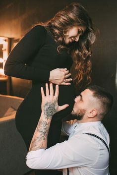 a pregnant woman is touching the belly of a man