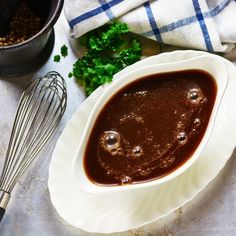 a white bowl filled with brown sauce next to other ingredients and utensils on a table