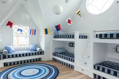 a room with bunk beds and rugs on the floor in front of two windows