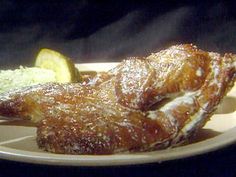 two pieces of fried fish on a plate with broccoli and lemon wedges