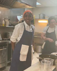 two people standing in a kitchen with pots and pans on the counter, one wearing an orange headband