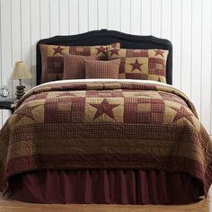 a bed with a red and brown bedspread on top of wooden flooring