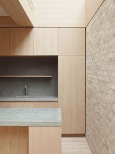 an empty kitchen with wooden cabinets and concrete counter tops, along with wood flooring