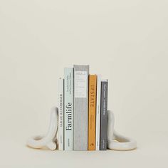 a stack of books sitting on top of each other in front of a white wall