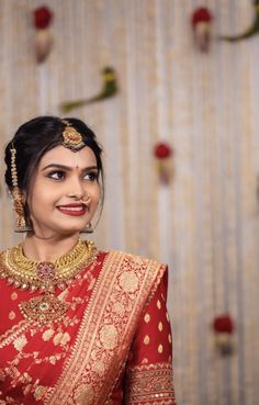 a woman wearing a red and gold sari with an elaborate necklace on her neck