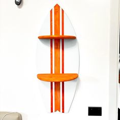 an orange and white surfboard mounted to the side of a wall with shelves on it