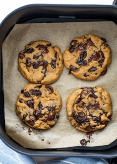 four chocolate chip cookies sitting on top of a pan