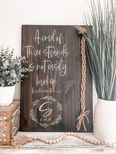 a wooden sign sitting on top of a shelf next to a potted plant and vase