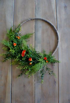 an arrangement of greenery is arranged on a wooden floor with a metal ring around it