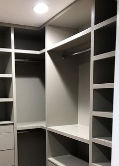 an empty walk in closet with white shelving and gray drawers on the bottom shelf