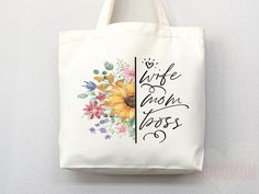 a white tote bag hanging on the wall with flowers and words written in black ink