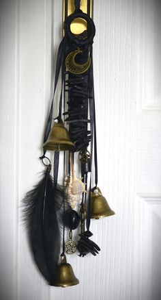 a clock with bells and feathers hanging from it's side on a wall next to a door