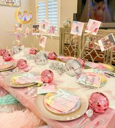 the table is set with pink and gold plates, napkins, and place settings