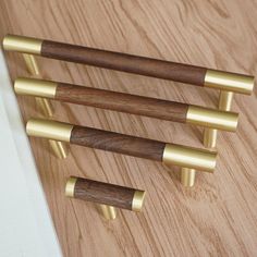 three brass and wood door handles on a wooden surface with white wall in the background