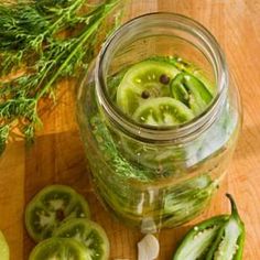 cucumber slices and dill in a jar on a wooden table with herbs