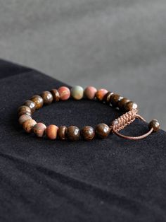 This bracelet is made with natural polished Bronzite Jasper and matte Picasso Jasper in size 8mm. Beautiful elegant yet minimalist design is perfect gift for self or your loved ones. Bracelet is 7'' long and has adjustable macrame knot that enables the cords to slide through and expand in size for comfortable fit.  Bronzite is used for protection, as it not only repels, but also sends back the negative energies to the sender. Spiritually, Bronzite assists us in achieving a state of certainty without willfulness, allowing us to easily adapt to the best path to take. It clears confusion, helping our ability to make decisions and choices about our life path. Bronzite is a "stone of courtesy", especially helpful to people who greet and assist the public. It will even instil a polite nature in Adjustable Jasper Beaded Bracelets With 8mm Beads, Adjustable Jasper Beaded Bracelets With Round Beads, Hand-strung Jasper Beaded Bracelets With Round Beads, Adjustable Brown Wristband With 8mm Beads, Earthy Jasper Round Bead Bracelets, Brown Agate Hand-strung Bracelets, Adjustable Jasper Bracelets With 8mm Beads, Hand-strung Brown Agate Bracelets, Adjustable Brown Jasper Bracelet