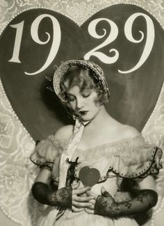 an old photo of a woman holding a heart with the number 929 on it