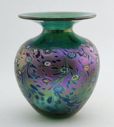 a green and purple vase sitting on top of a white table