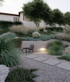 an outdoor patio area with gravel, grass and plants on the side of the house