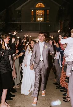 a bride and groom walk down the aisle with sparklers in their hands as they exit