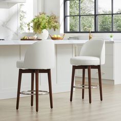 two white stools sitting in front of a kitchen counter