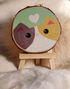 a close up of a wood slice with two cats on it's face and heart eyes