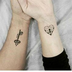 two people are holding hands with tattoos on their wrists and the other hand has a key in it