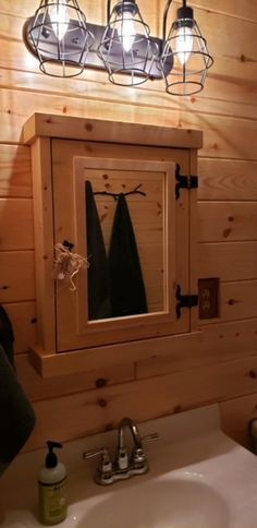 a bathroom with a sink, mirror and lights on the wall next to wood paneled walls