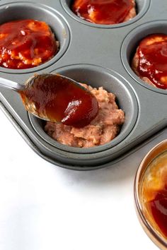 a muffin tin filled with cupcake batter and covered in ketchup sauce