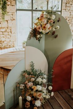 flowers and greenery are arranged on the side of a wall in front of a window