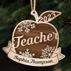 a wooden ornament hanging from a christmas tree with the name teacher on it