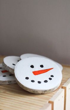 three coasters with a painted snowman on them sitting on top of a wooden table