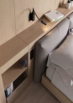 a bed with a book shelf next to it and a lamp on the headboard