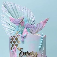 a pink and blue cake with mermaid decorations